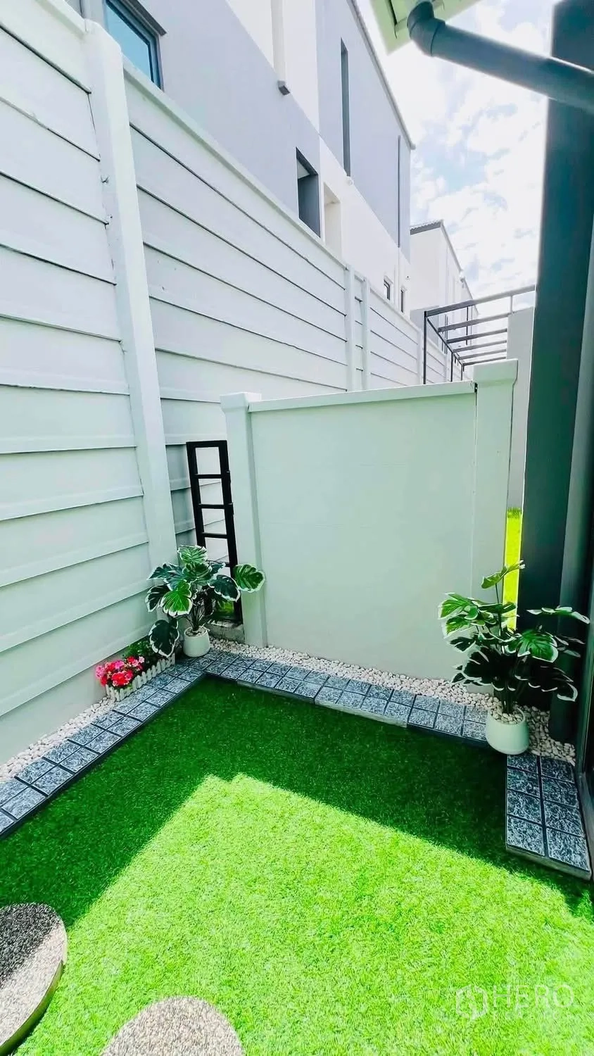 ทาวน์เฮาส์ for rent in Bang Phli, Samut Prakan - ลานสวนส่วนตัวล้อมรั้ว ปูหญ้าเทียม ตกแต่งกระถางต้นไม้และแผ่นทางเดิน