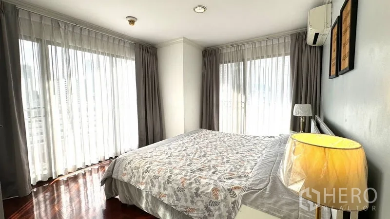คอนโด ให้เช่าหรือขายในWatthana, Bangkok - ห้องนอนหลักมุมอาคาร พร้อมหน้าต่างรอบด้าน ผ้าม่านโปร่ง และโคมไฟหัวเตียง