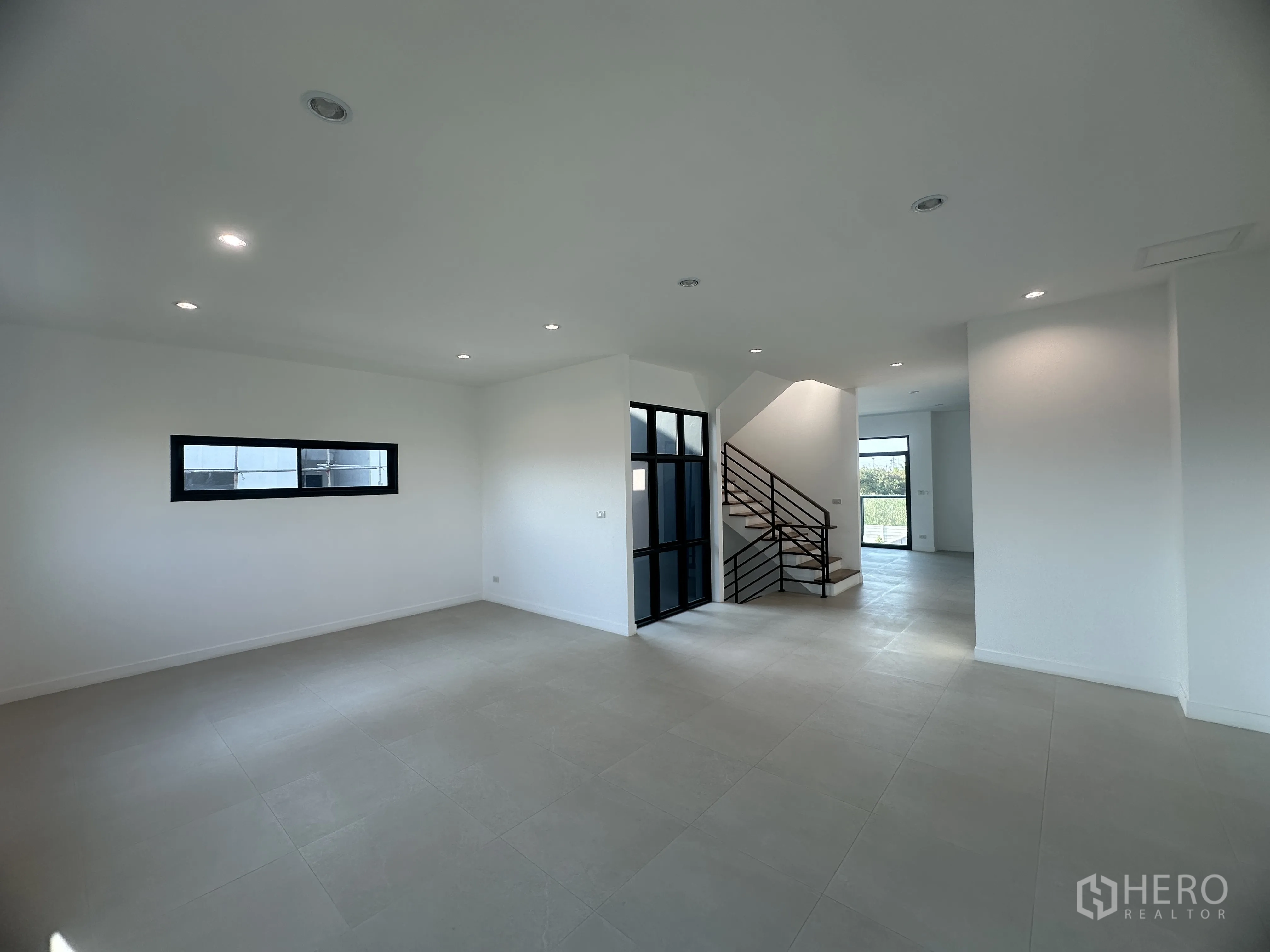 Home Office for sale in Khlong Luang, Pathum Thani - Modern living space with tiled floors, black-framed glass partition, and staircase.