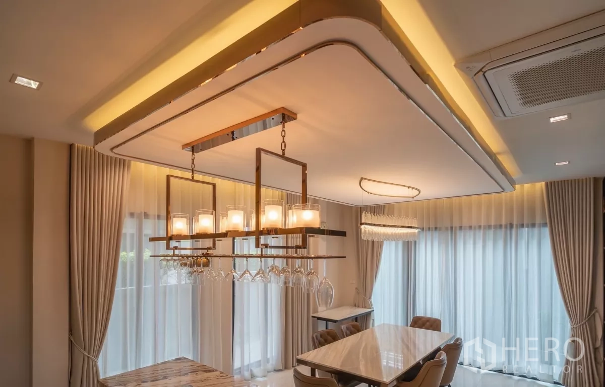 Detached House for rent or sale in Saphan Sung, Bangkok - Tray‑ceiling lighting and pendant fixture above the dining table with sheer curtains.