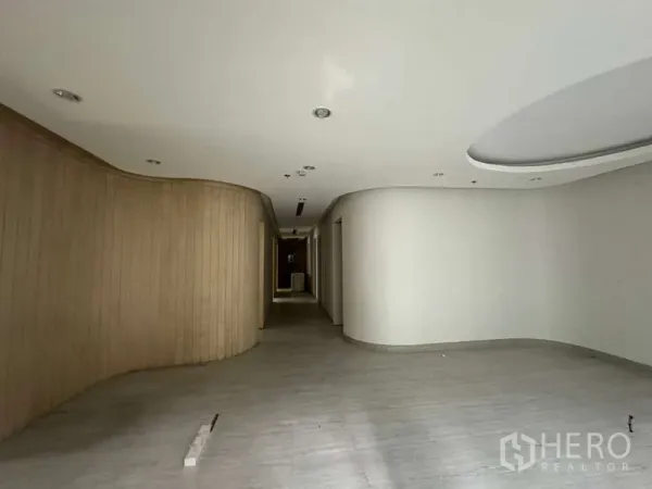 零售空间 出租在Pathum Wan, Bangkok - 空置零售室内，弧形木质特色墙与嵌入式射灯。