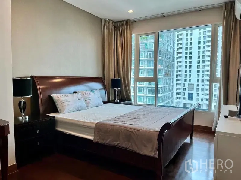 Condominium for rent in Watthana, Bangkok - Master bedroom close-up of bed by corner windows overlooking neighboring towers.