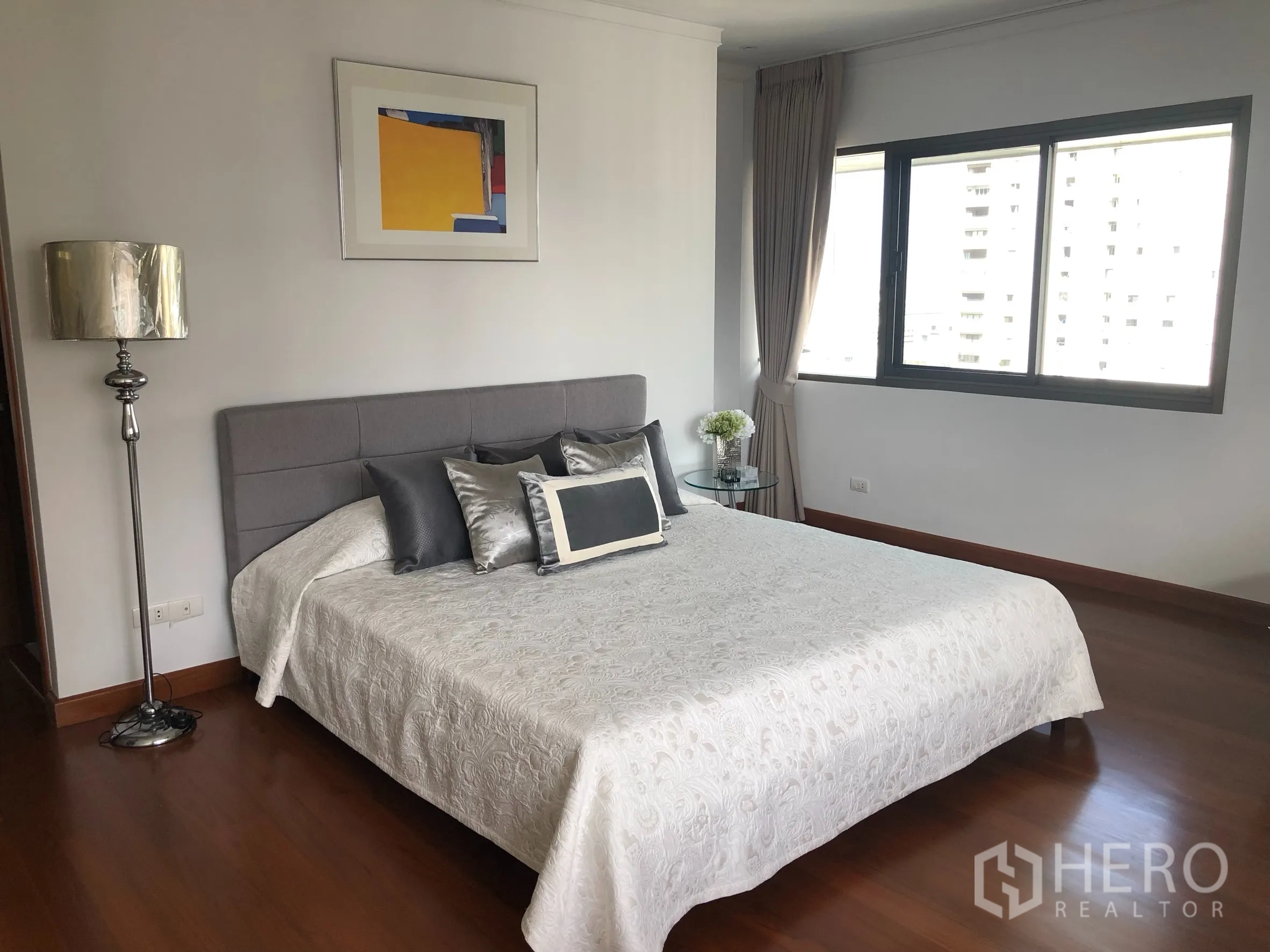 คอนโด ให้เช่าในBangkok - ห้องนอนใหญ่ เตียงหัวเตียงผ้านุ่มสีเทา หน้าต่างบานกว้าง พื้นไม้