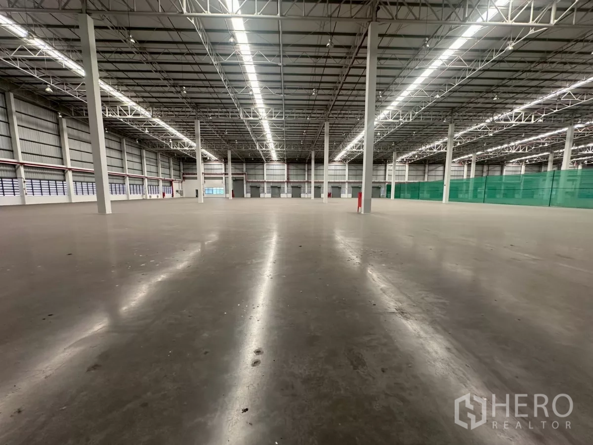 Warehouse for rent in Bang Phli, Samut Prakan - Interior view toward dock doors with bright LED lighting and fire equipment.
