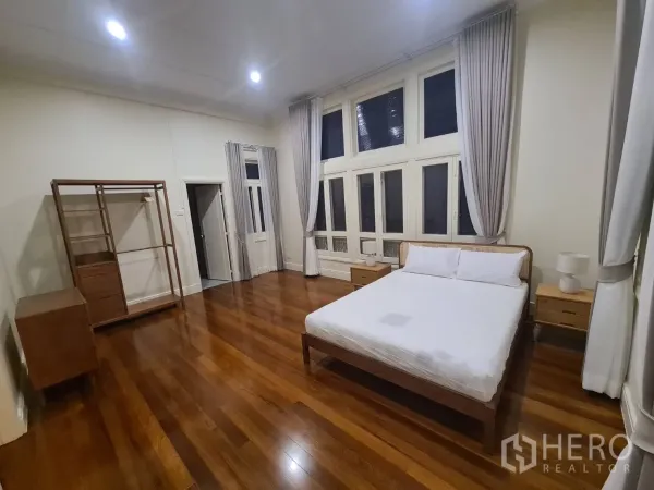 บ้าน ให้เช่าในKhlong Toei, Bangkok - ห้องนอนสว่างโปร่ง หน้าต่างสูงเต็มผนัง ผ้าม่าน และพื้นไม้โทนอุ่น