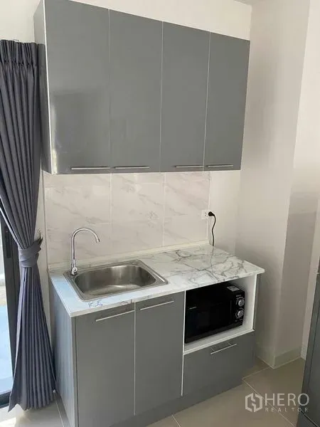 联排别墅 出租在Prawet, Bangkok - 现代曼谷联排别墅内的灰色一体式小厨房，配大理石台面、水槽与微波炉。