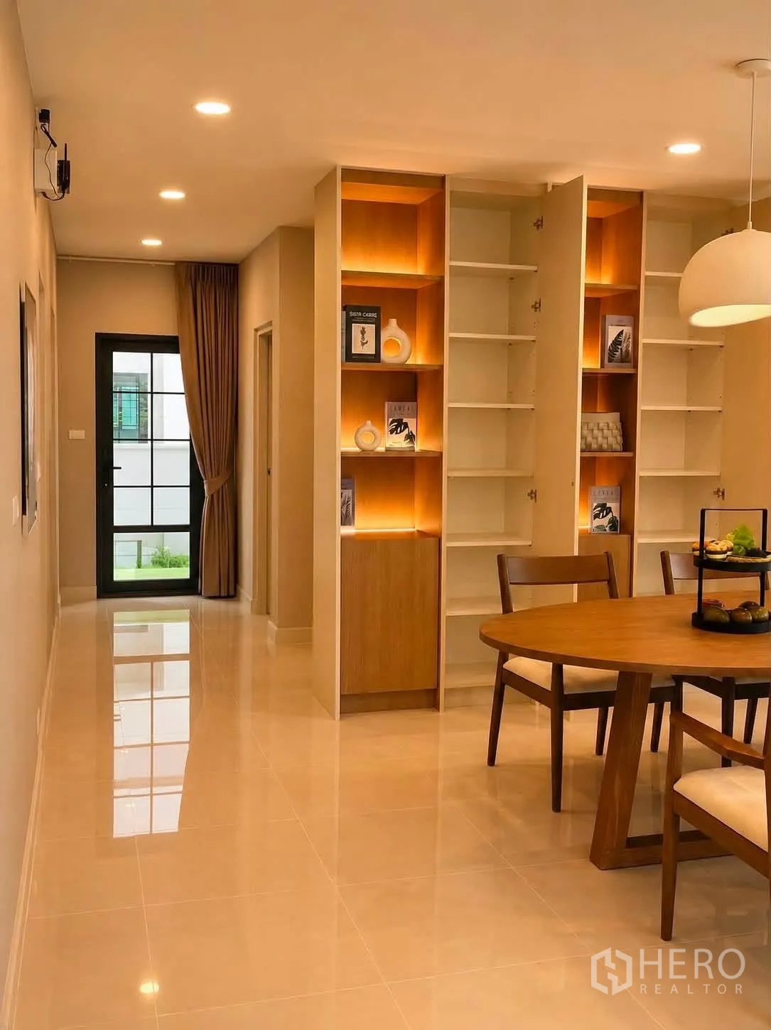 独栋房屋 for rent in Bang Phli, Samut Prakan - 走廊与餐区，背光展示柜与圆形木桌相映成趣。
