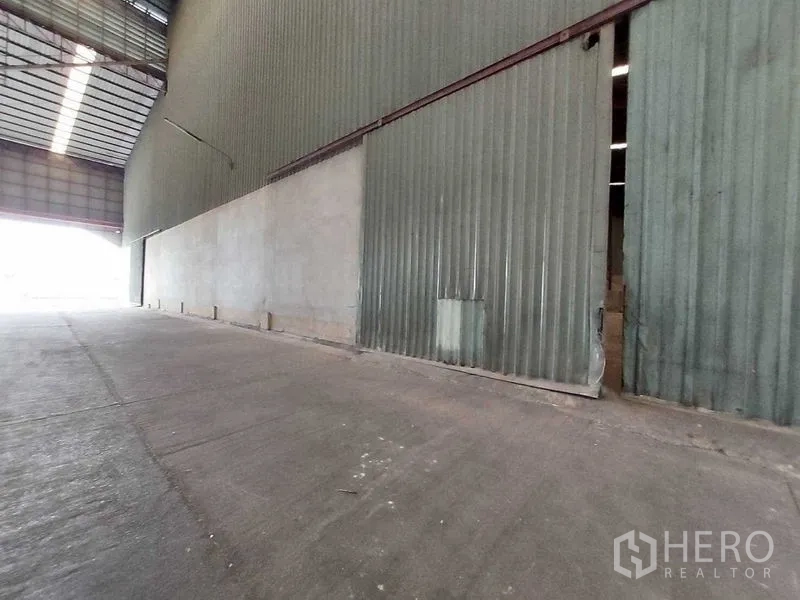 Warehouse for rent in Lat Lum Kaeo, Pathum Thani - Side angle of extended sliding doors and smooth concrete loading zone.