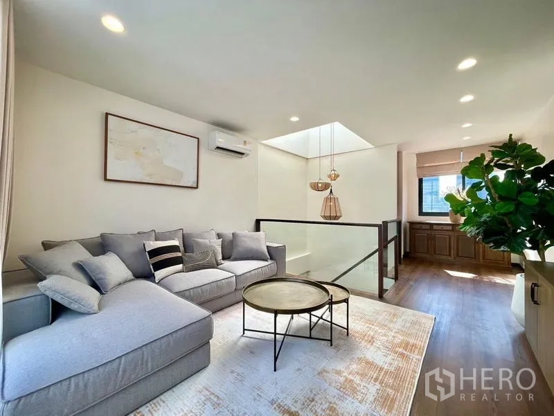 Townhouse for rent - Upper lounge with skylight, sofa, and built-in cabinets beside a window.