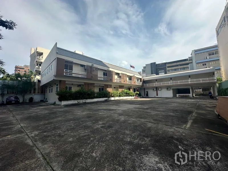 Home Office for rent in Chatuchak, Bangkok - Wide view of two low-rise buildings with a large parking forecourt.