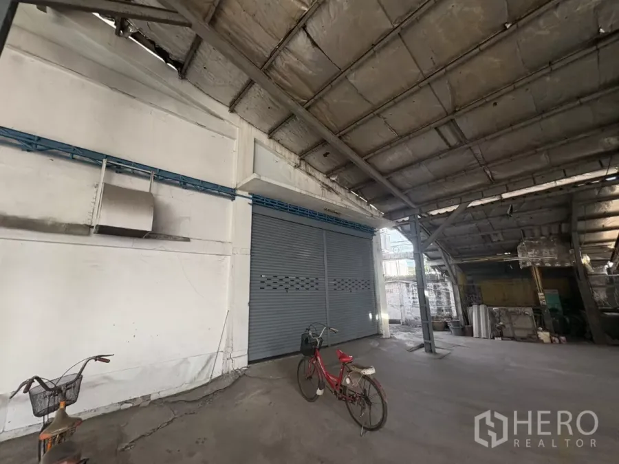 Warehouse for rent in Khlong Toei, Bangkok - Covered loading area with steel roof, roller shutter warehouse door and concrete floor.