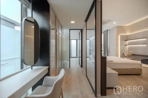 Detached House for rent in Saphan Sung, Bangkok - Hallway with vanity desk, floor-to-ceiling glass wardrobes and timber flooring leading to a bedroom.