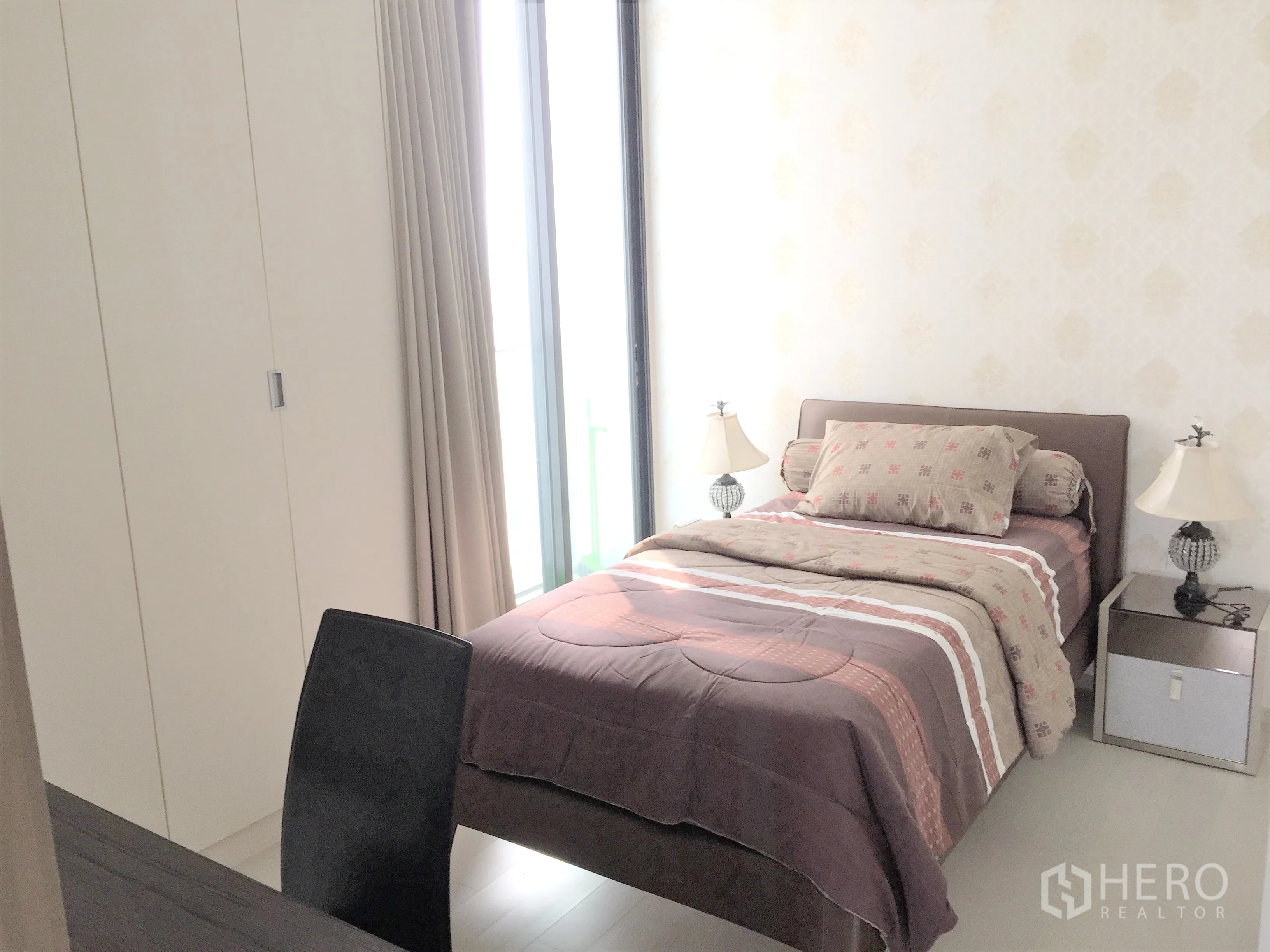 Condominium for rent in Pathum Wan, Bangkok - Sunlit bedroom with floor-to-ceiling windows, built-in wardrobe and bedside tables.