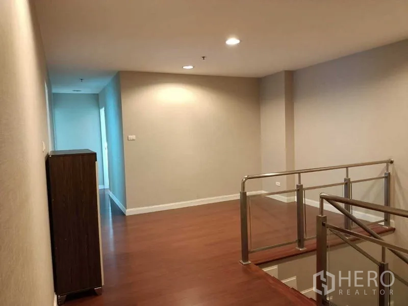 Condominium for rent or sale in Huai Khwang, Bangkok - Upper-floor landing with recessed lighting and glass-and-steel stair railing.