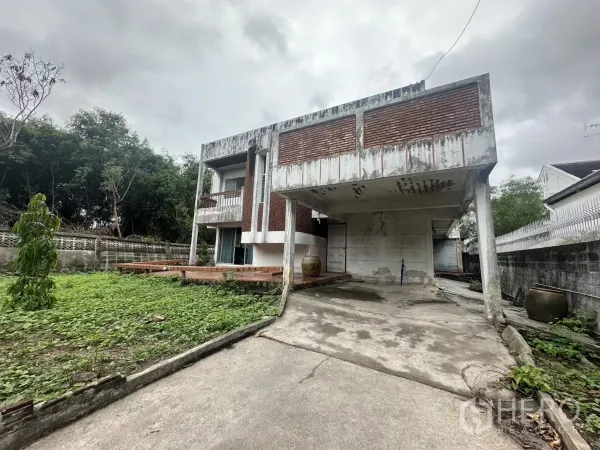 独立式住宅 出售在Phra Khanong, Bangkok - 两层独栋住宅，带顶棚车位、阳台与大草坪，位于帕卡农Bang Chak，阴天拍摄。