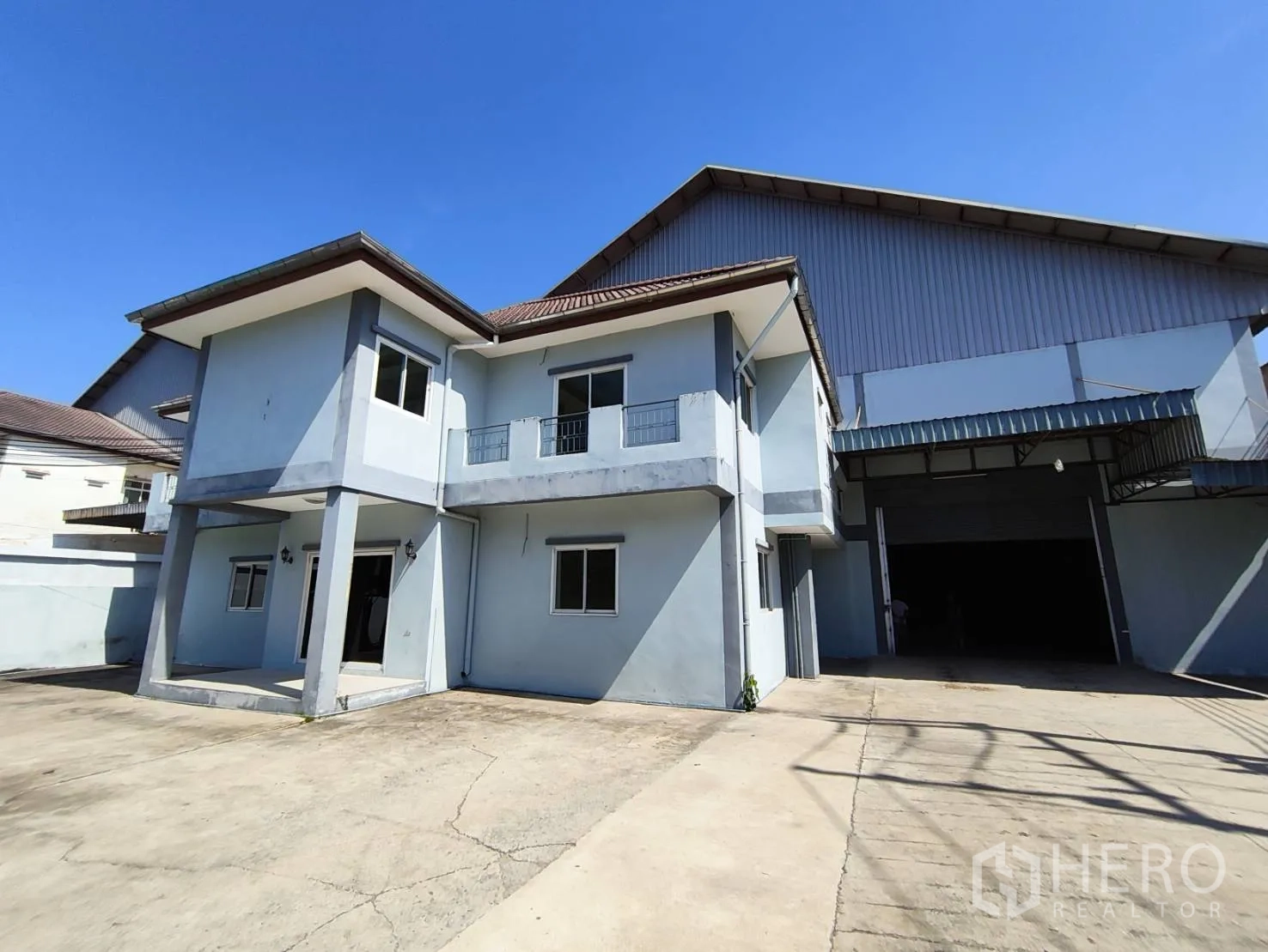 Factory for rent in Krathum Baen, Samut Sakhon - Two-storey house attached to a large factory building with a wide concrete forecourt.