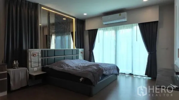 บ้าน ให้เช่าหรือขายในBang Na, Bangkok - ห้องนอนใหญ่พร้อมหัวเตียงบุนวม ผ้าม่านทึบ และประตูบานเลื่อนออกระเบียง