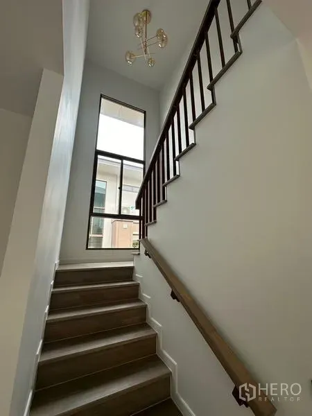 Detached House for rent in Bang Kapi, Bangkok - Staircase with wooden handrail, tall window and contemporary chandelier.