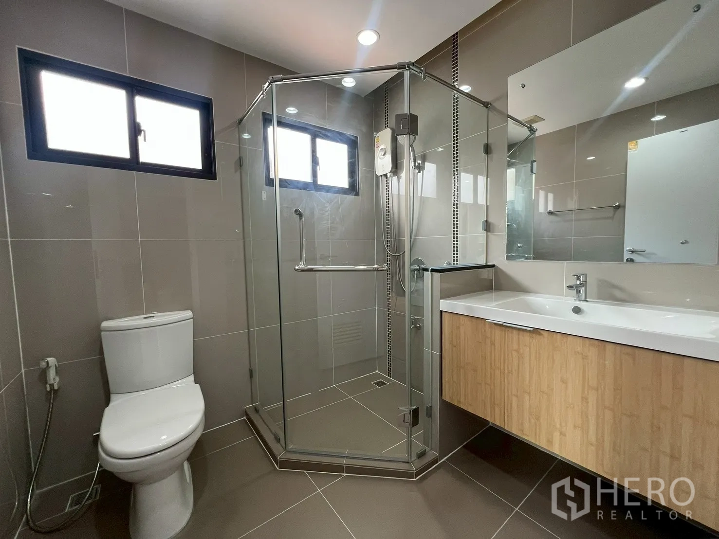 Detached House for rent or sale in Bang Phli, Samut Prakan - Contemporary bathroom with glass shower enclosure, toilet and wide vanity.