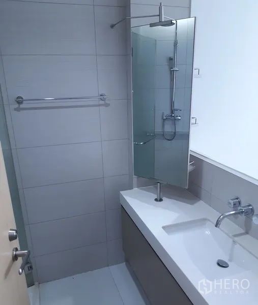 คอนโด ให้เช่าในKhlong Toei, Bangkok - ห้องน้ำสมัยใหม่พร้อมเคาน์เตอร์อ่างล้างหน้ายาว ก๊อกติดผนัง กระจก และพื้นที่อาบน้ำแบบฉากกั้น