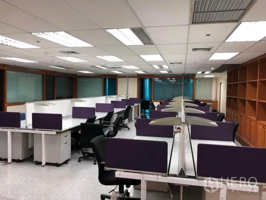 办公空间 出租在Din Daeng, Bangkok - 大型工位区，长排桌、紫色挡板与整面书架。