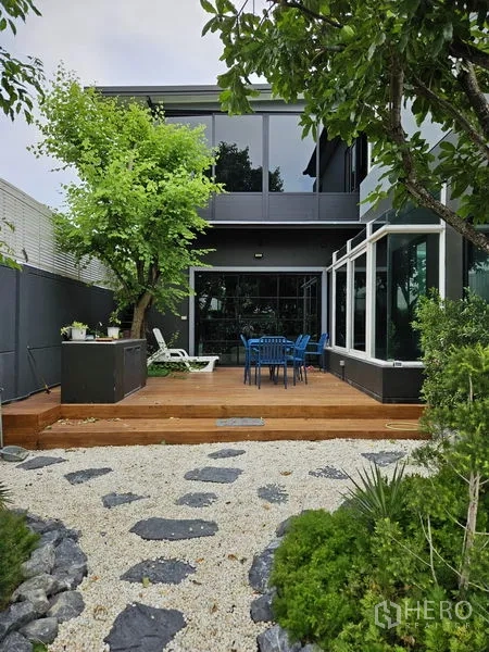 Detached House for sale in Thawi Watthana, Bangkok - Rear wooden deck patio with outdoor dining set and a glass sunroom.