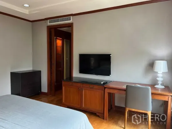 คอนโด ให้เช่าหรือขายในPhra Khanong, Bangkok - มุมห้องนอนพร้อมทีวีติดผนัง โต๊ะทำงานไม้ และประตูเชื่อมเข้าห้องน้ำ