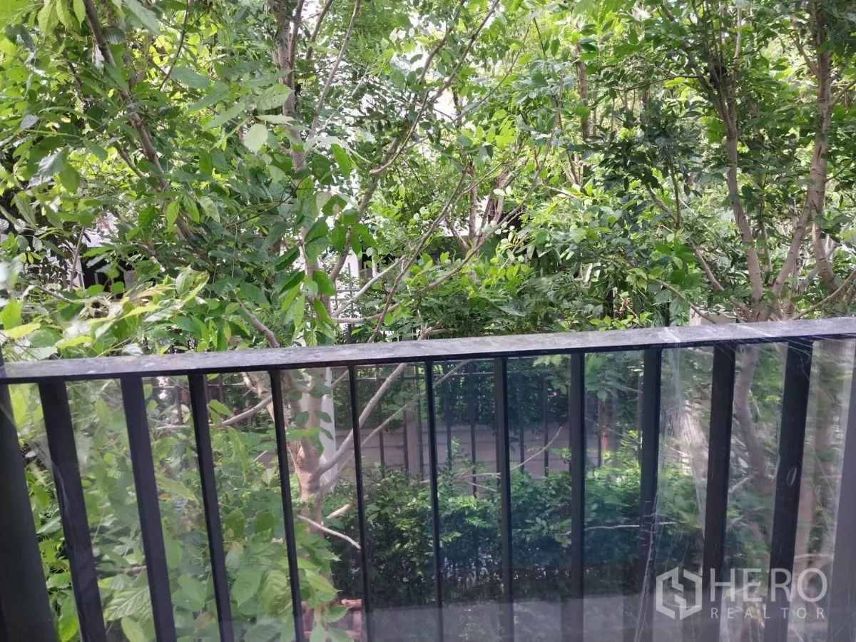 Townhouse for rent in Khlong Toei, Bangkok - Balcony with glass railing overlooking mature trees and greenery.