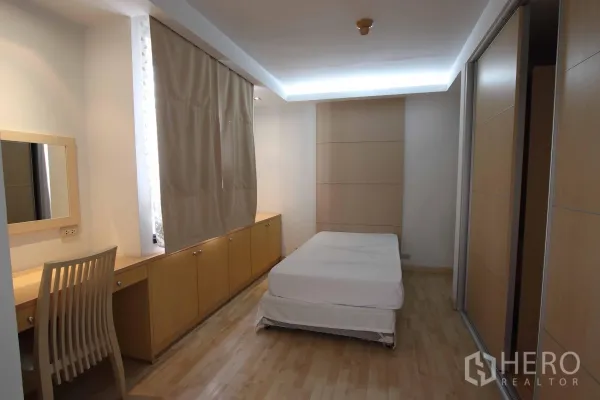 公寓 出租在Watthana, Bangkok - 第二卧室配木地板、内置柜与长书桌，天花暗槽灯柔和。