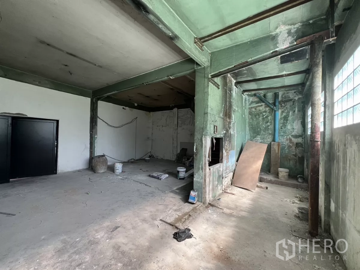 店屋 出售在Suan Luang, Bangkok - 一层毛坯区，绿色钢梁与黑色入口门一字排开。