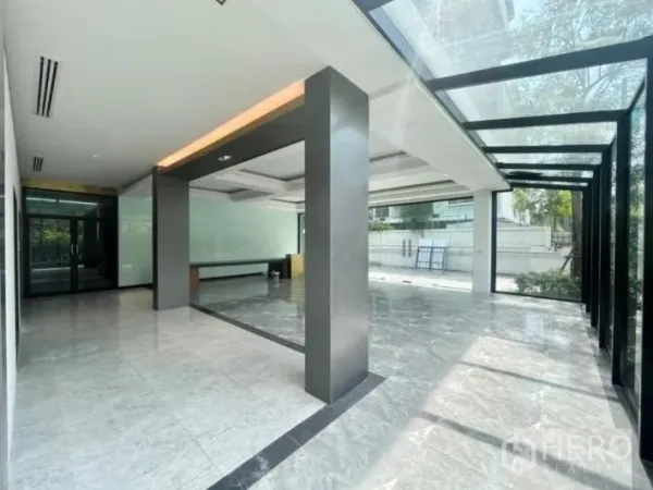 Detached House for rent or sale in Khlong Toei, Bangkok - Glass-roofed walkway and airy hall with marble tiles and dark structural columns.