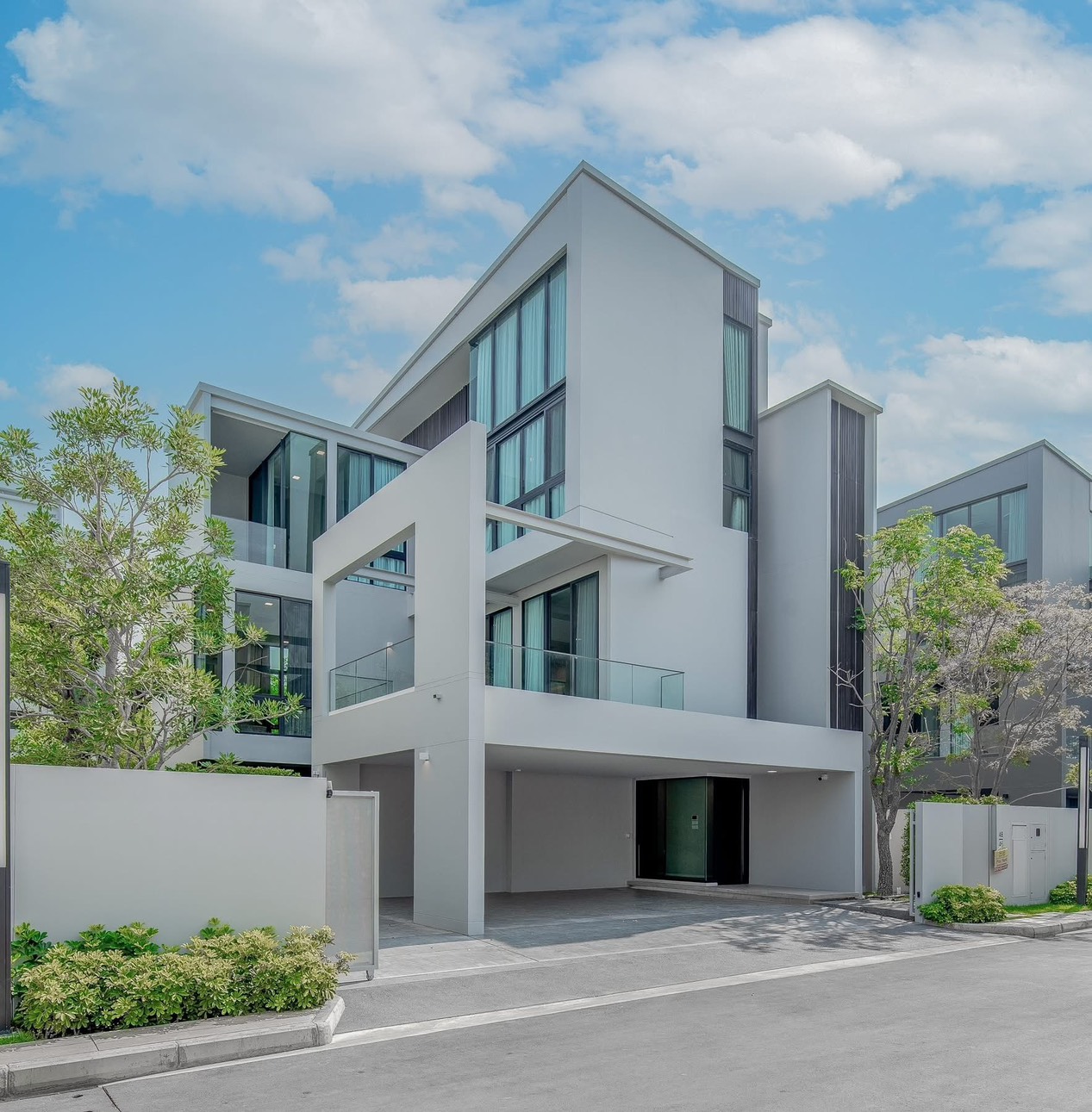 Detached House for rent in Saphan Sung, Bangkok - Modern three-storey detached house exterior with glass balconies, carport and landscaped entry.