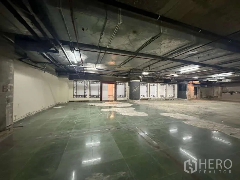 零售空间 出租 - 宽阔零售内场，绿色地砖、空置橱窗与外露机电管线。