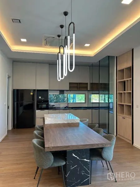 Detached House for rent in Saphan Sung, Bangkok - Kitchen with wood dining island, pendant lights and reflective glass cabinetry.