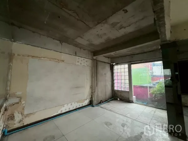 店屋 出租在Watthana, Bangkok - 一层毛坯空间，混凝土顶、地砖与一面大玻璃砖窗。