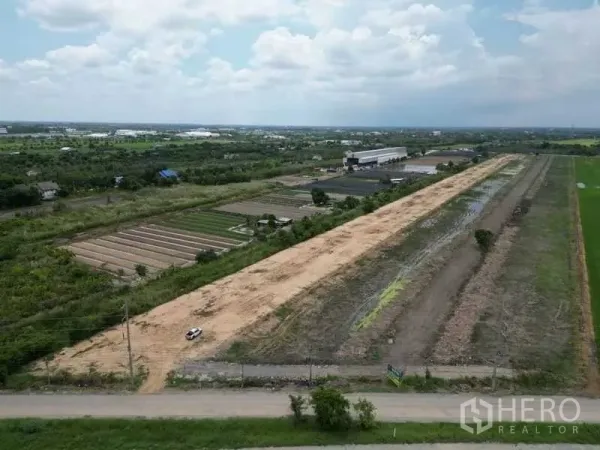 Land for sale in Sai Noi, Nonthaburi - Aerial view of a long rectangular land plot with road frontage, level soil, and neighboring farms and a warehouse in Sai Noi, Nonthaburi.
