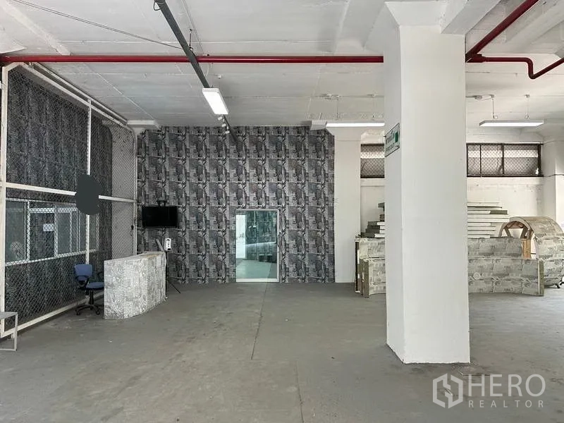 Factory for rent in Mueang Samut Prakan, Samut Prakan - Ground-floor production area with columns, mesh partition and fire sprinkler piping.