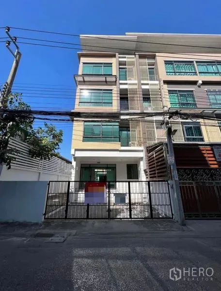 Townhouse for rent or sale in Bang Kho Laem, Bangkok - Four-storey townhouse facade with green-tinted windows and gated parking.