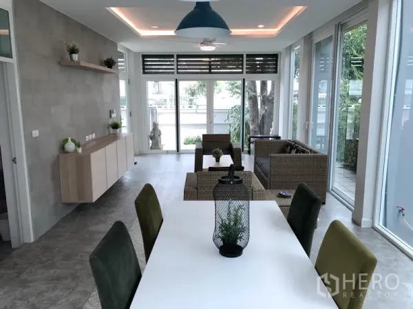 Detached House for rent or sale in Huai Khwang, Bangkok - Dining table with pendant lighting facing floor-to-ceiling windows and sliding doors to the terrace.