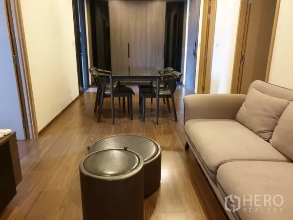 คอนโด ให้เช่าในWatthana, Bangkok - มุมนั่งเล่นอบอุ่น โซฟาสีเบจ โต๊ะซ้อน และชุดโต๊ะทานอาหารบนพื้นไม้