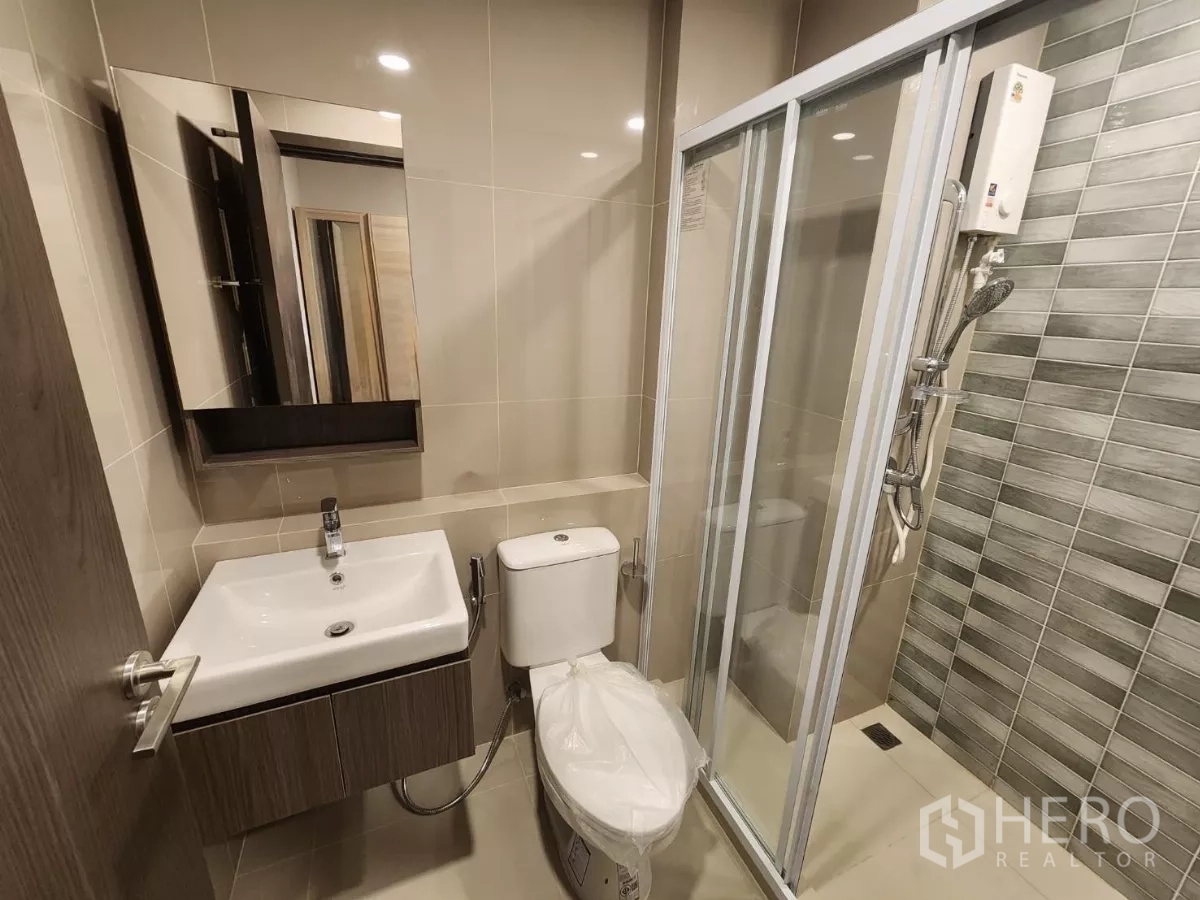 Townhouse for rent in Khlong Toei, Bangkok - Second view of tiled bathroom with glass shower and vanity.