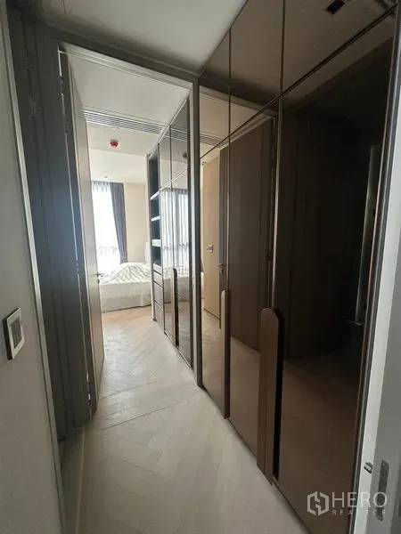 Condominium for rent - Hallway with mirrored built-in wardrobes leading to a sunlit bedroom.