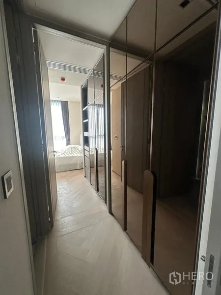 Condominium for rent - Hallway with mirrored built-in wardrobes leading to a sunlit bedroom.