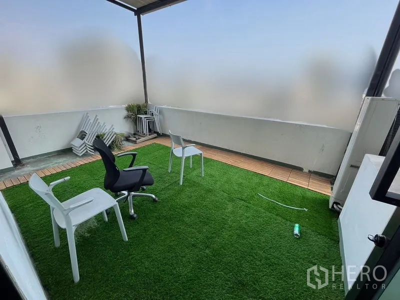 办公空间 出租在Khlong Toei, Bangkok - 带人造草坪的私人露台，摆放椅子，磨砂屏风遮挡部分城市景观。