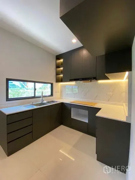 Detached House for sale in Don Mueang, Bangkok - L-shaped modern kitchen with matte black cabinets, marble backsplash, under-cabinet lighting and a window.