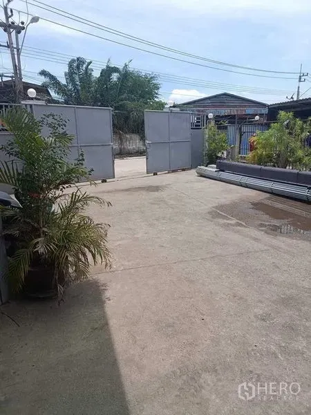 คลังสินค้า ขายในSamut Sakhon - ลานคอนกรีตกว้างภายในพื้นที่รั้วรอบขอบชิด พร้อมประตูเหล็กบานเลื่อนและกระถางต้นไม้