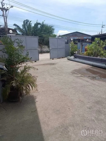คลังสินค้า ขายในSamut Sakhon - ลานคอนกรีตกว้างภายในพื้นที่รั้วรอบขอบชิด พร้อมประตูเหล็กบานเลื่อนและกระถางต้นไม้