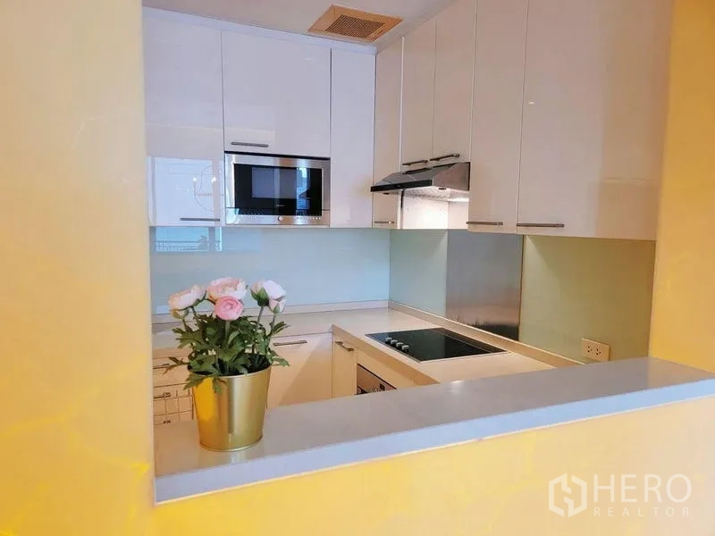 คอนโด ให้เช่าในWatthana, Bangkok - เคาน์เตอร์ครัวและตู้ พร้อมเตาไฟฟ้า ไมโครเวฟ และกระถางดอกไม้ตกแต่ง