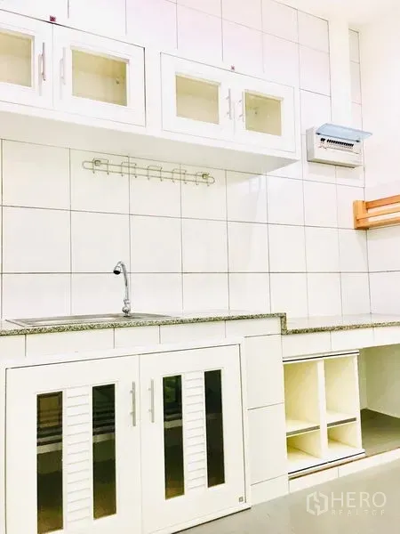 联排别墅 出租在Prawet, Bangkok - 白色瓷砖厨房，带上柜、水槽与石质台面。