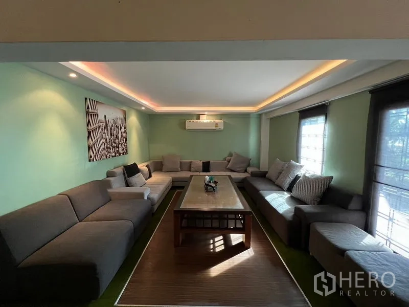 店屋 出租在Suan Luang, Bangkok - 舒适客厅，环形长沙发、茶几与柔和天花灯光。